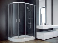 Fragment łazienki. Zbliżenie na kabinę prysznicową narożną ze srebrną armaturą prysznicową. Po prawej stronie białe szafki i lustro