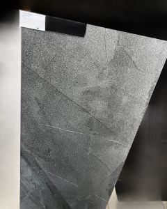 Szara płytka imitująca kamień o matowej trójwymiarowej powierzchni. Ciemne tło