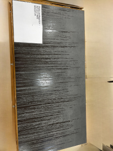 Szara płytka z cieniowaną kaskada połyskującym kresek różnej długości spływających w dół. Karton w tle