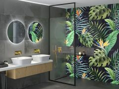Fragment łazienki z czarną ścianką prysznicową walk-in, złotą armaturą i połączeniem szarych, drewnopodobnych i imitujących wzory roślinne płytek